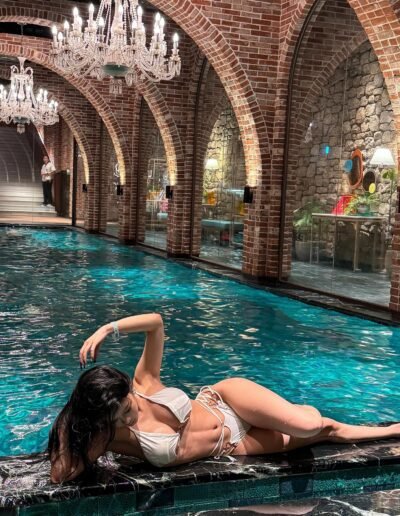 Escort with cascading black hair leaning back, highlighting her alluring curves.